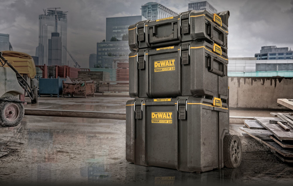 Skrzynka narzędziowa DEWALT DS450 plac budowy trzy skrzynie ustawione jedna na drugiej w tle budynki możliwość mocowania modułów o połowie szerokości w górnej części skrzyni znajduje się element umożliwiający zamocowanie pół-organizerów dostosować konfigurację skrzyni