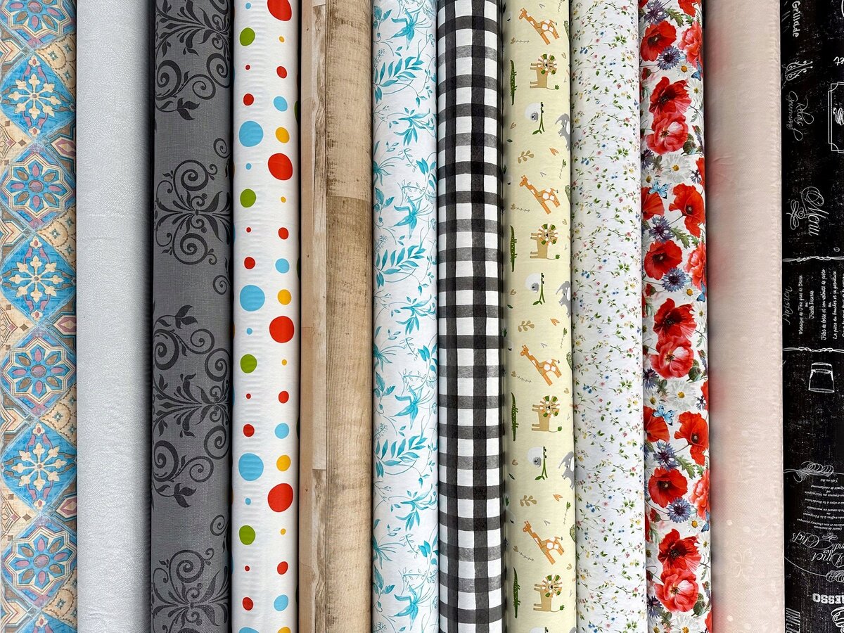 Na obrazie widoczne są różne wzory cerat na rolkach, w tym motywy kwiatowe, geometryczne, w kratkę oraz z postaciami zwierząt. Każda rolka ma inny wzór i kolorystykę, od jasnych po ciemne odcienie.