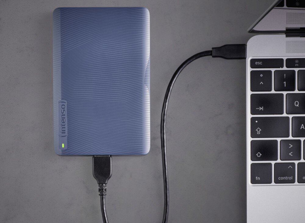 Dysk INTENSO Memory Safe Prostokątny dysk zewnętrzny z falistym wzorem ułożony pionowo, podłączony czarnym przewodem do portu w bocznej krawędzi obudowy laptopa, pojemność, złącze, format, prędkość