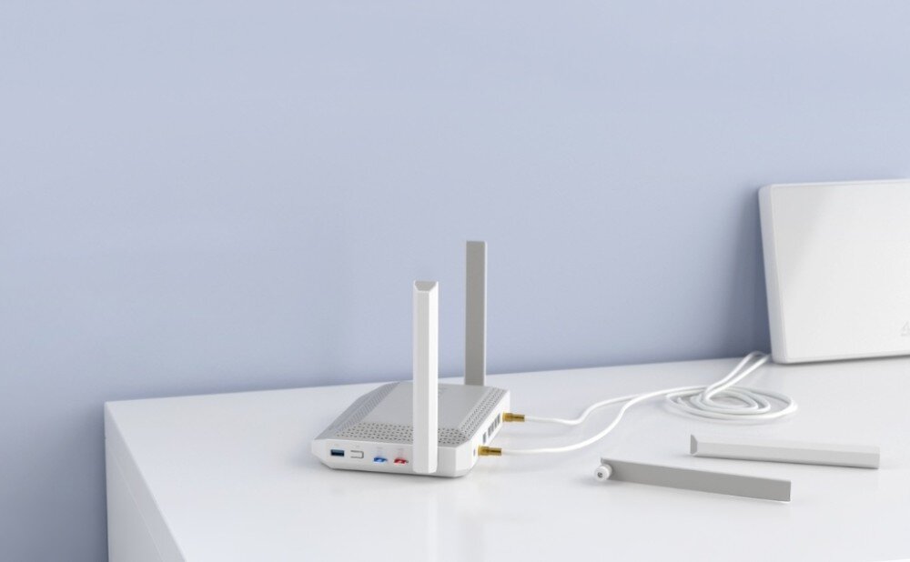 Router KEENETIC Hopper 4G+ Urządzenie sieciowe z dwiema zamontowanymi pionowo antenami leży na białym blacie, a obok znajdują się dwie odłączone anteny i zwinięty biały przewód