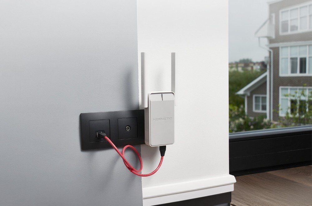 Wzmacniacz sieci KEENETIC Buddy 6 Białe prostokątne urządzenie z dwiema antenami połączone krótkim czerwonym kablem z czarnym gniazdkiem na ścianie