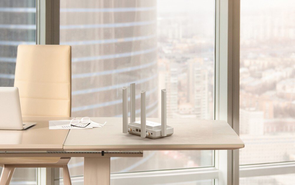 Router KEENETIC Speedster 4G+ Biały ruter z czterema antenami na krawędzi biurka przy dużym oknie z widokiem na wieżowce