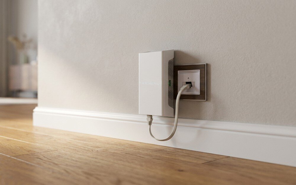 Wzmacniacz sieci KEENETIC Buddy 6 SE Widok z boku na białe urządzenie połączone kablem z gniazdkiem na beżowej ścianie nad jasną podłogą