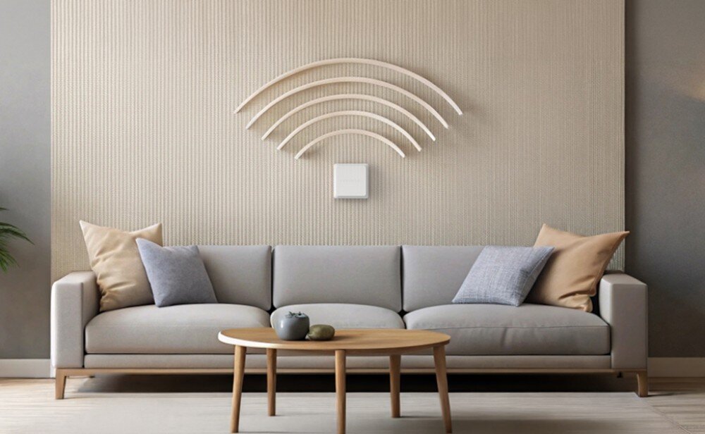 Router KEENETIC Challenger SE Białe kwadratowe urządzenie zamontowane na ścianie nad szarą kanapą pod dekoracją w kształcie symbolu sieci bezprzewodowej