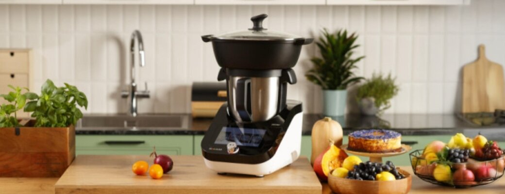 Termorobot iCoook  MRK-38 na kuchennym blacie, obok owoce i ciasto.