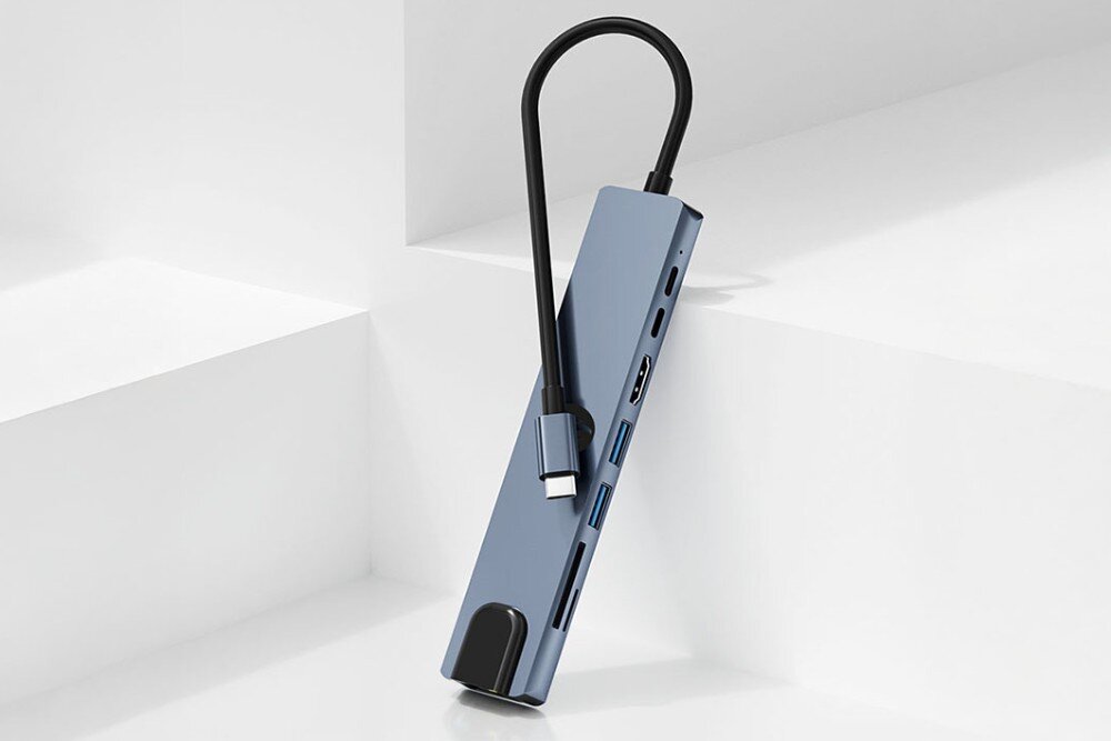 Hub HAWK HW-HUB801 8w1 Hub USB-C w kolorze niebieskoszarym oparty o białą powierzchnię schodków. Przewód USB-C owinięty wokół urządzenia, na obudowie znajduje się czarne logo, obudowa, wygląd, materiał