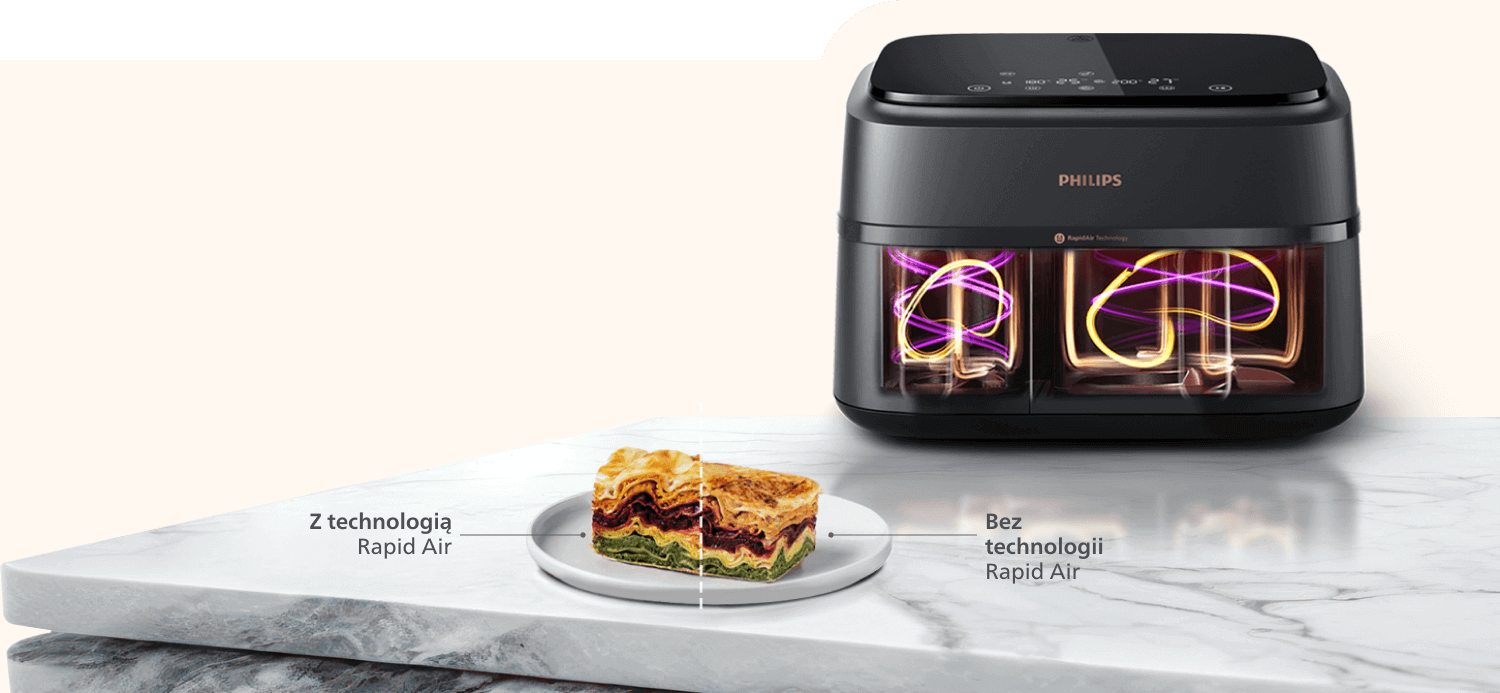 Na marmurowym blacie stoi czarna frytkownica beztłuszczowa z dwoma przezroczystymi koszami, na których widać kolorowe linie. Obok na talerzu znajduje się kawałek zapiekanki z opisem \'Z technologią Rapid Air\' i \'Bez technologii Rapid Air\'.