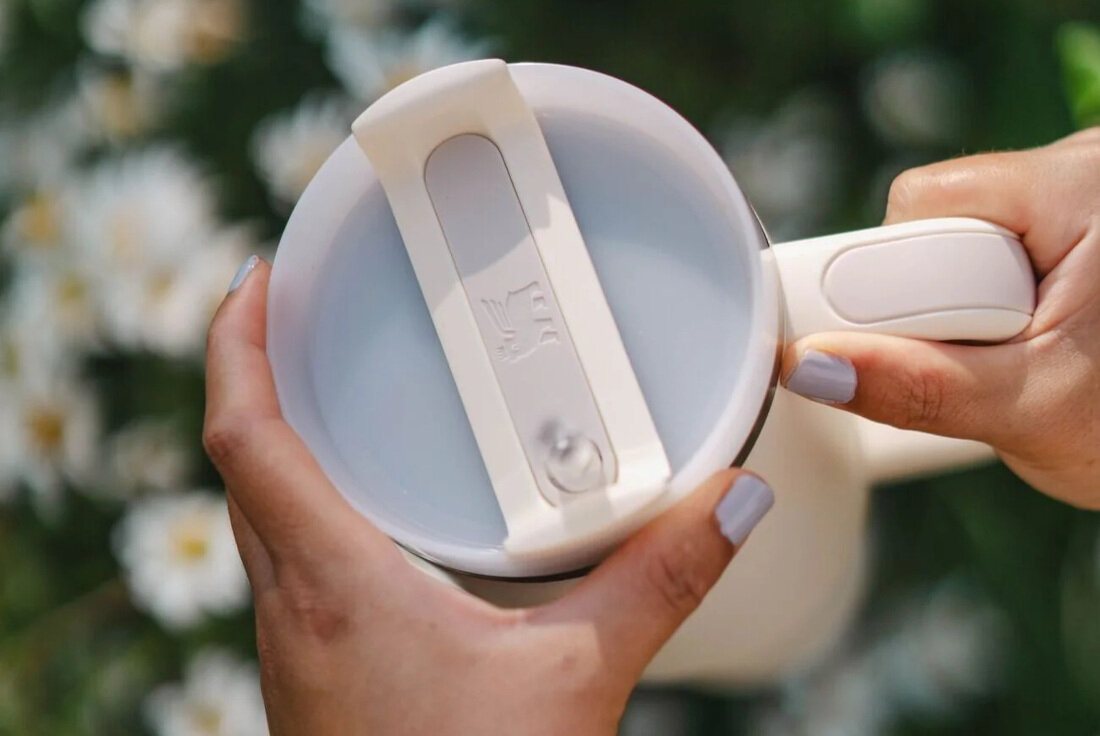 Kubek termiczny STANLEY Quencher H2.0 FlowState Tumbler trzymany w ręce przez uśmiechniętą osobę