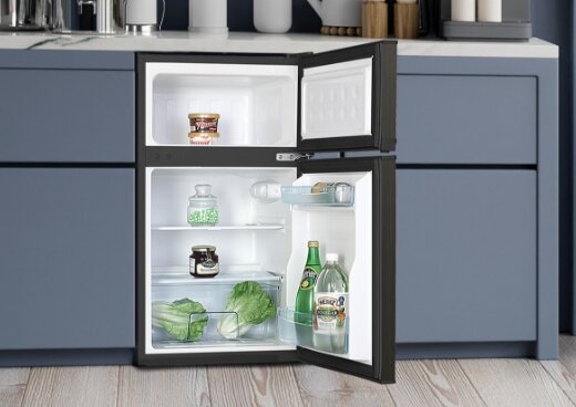 Otwarta lodówka MPM-87-CZ-14/E w zabudowie kuchennej. W urządzeniu żywność.