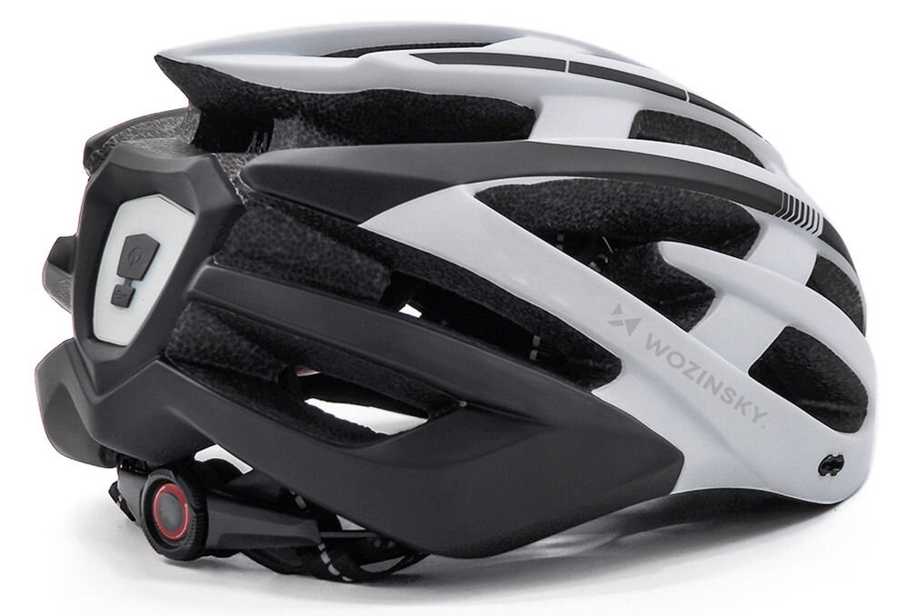 Czarno-biały kask rowerowy z napisem \'WOZINSKY\' i wbudowaną lampką z tyłu. Kask ma aerodynamiczny kształt z licznymi otworami wentylacyjnymi.