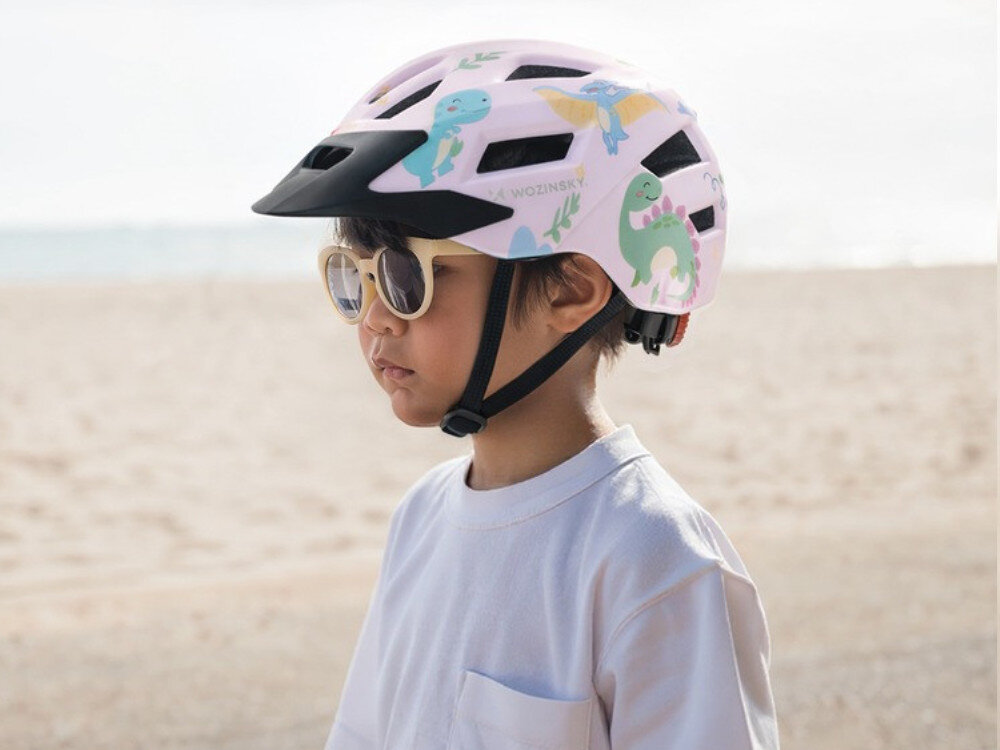 Kask rowerowy WOZINSKY HT-45R Różowy dla Dzieci (rozmiar XS), wentylacja, lekkość, chłodzenie, wygoda, Profil chłopca w różowym kasku na tle plaży.