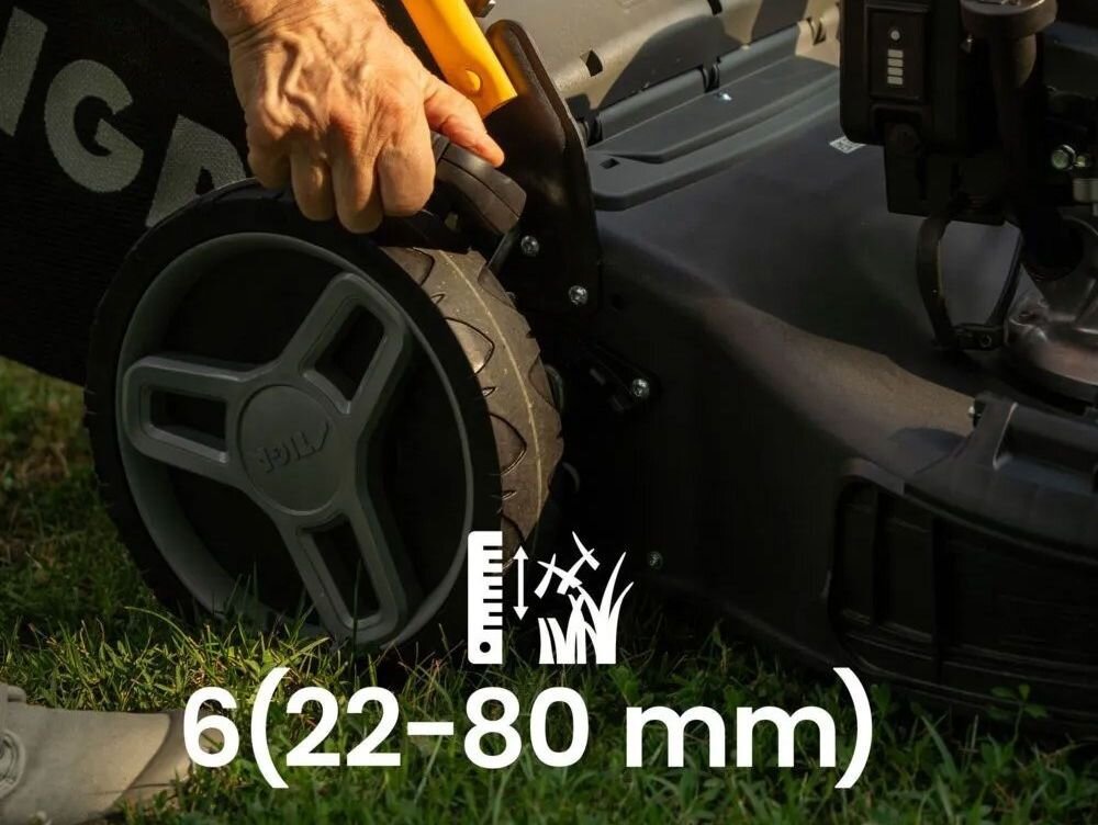 Osoba reguluje wysokość kosiarki, trzymając uchwyt przy kole. Na obrazie widoczny jest tekst: \'6(22-80 mm)\'.
