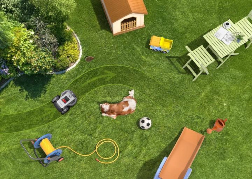 Na trawniku znajduje się robot koszący, pies, piłka, wąż ogrodowy na bębnie, domek dla psa, zabawkowa ciężarówka, stół z krzesłami oraz konewka. Widoczne są ślady koszenia trawy w formie linii.