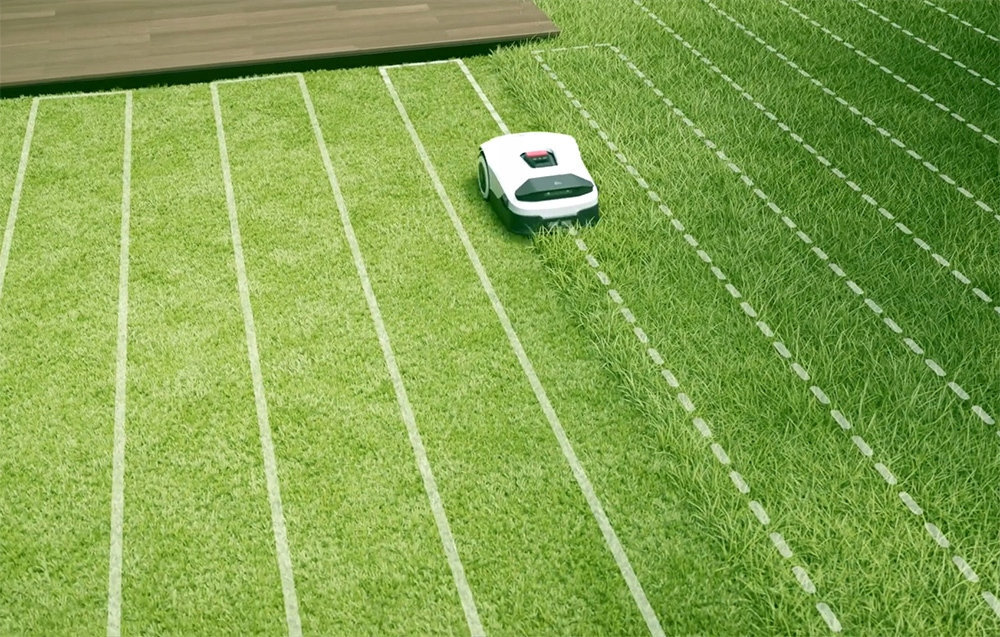 Robot koszący ANTHBOT Genie 800 Bez przewodu ograniczającego ogród trawnik robot stoi na trawie białe kreski wyznaczające kierunek jazdy robota brak przewodu ograniczającego zintegrowana kamera AI odbiornik RTK aplikacja Anthbot App ręcznie wyznaczyć różne strefy koszenia automatycznie rozpoczyna pracę w wybranych strefach