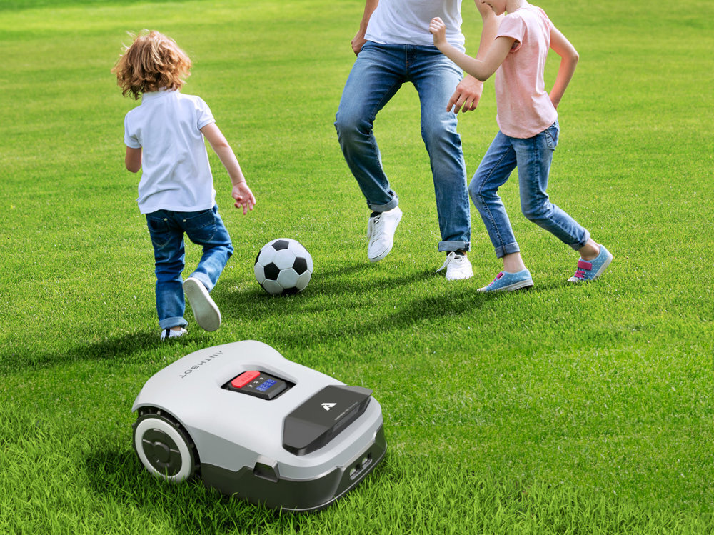 Robot koszący ANTHBOT Genie 3000 Bez przewodu ograniczającego trawnik robot stoi na trawie w tle trzy osoby grają w piłkę wymiary 63 x 41 x 27 cm wbudowany wyświetlacz bezszczotkowy silnik długa eksploatacja