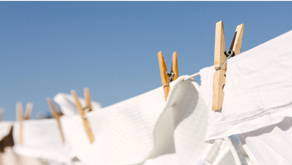 SUSZARKA BOSCH WQG244CSPL Na zdjęciu „024.jpg” widać białe pranie rozwieszone na sznurku na świeżym powietrzu, przypięte drewnianymi klamerkami. W tle bezchmurne, niebieskie niebo. Zdjęcie przedstawia klasyczny sposób suszenia ubrań na dworze program czasowy suszenie małej ilości ubrań delikatne tkaniny wielowarstwowe kosz do suszenia wełny obuwia dostosowanie do wilgotności resztkowej efektywne powtarzalne cykle