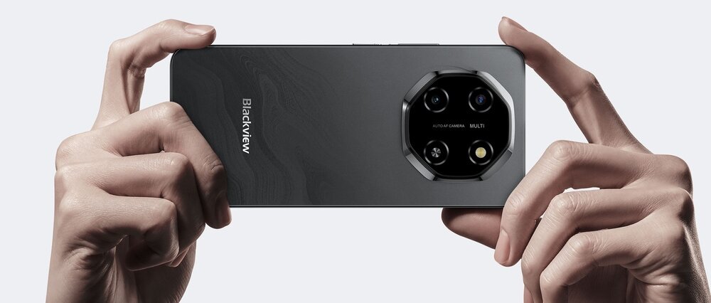 Osoba trzyma smartfon z widocznym logo \'Blackview\' na tylnej obudowie. Telefon ma aparat z trzema obiektywami i lampą błyskową w sześciokątnym module.