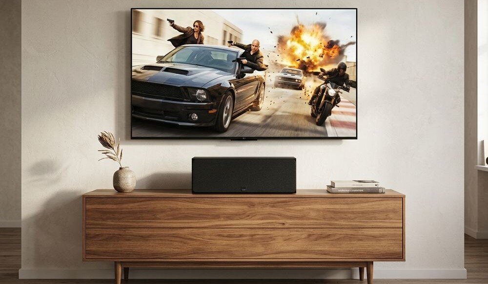 Głośnik centralny DALI Sonik Cinema ustawienie LCR poziome pionowe elastyczna konfiguracja, kolumna głośnikowa stojąca na komodzie pod zawieszonym telewizorem w pomieszczeniu