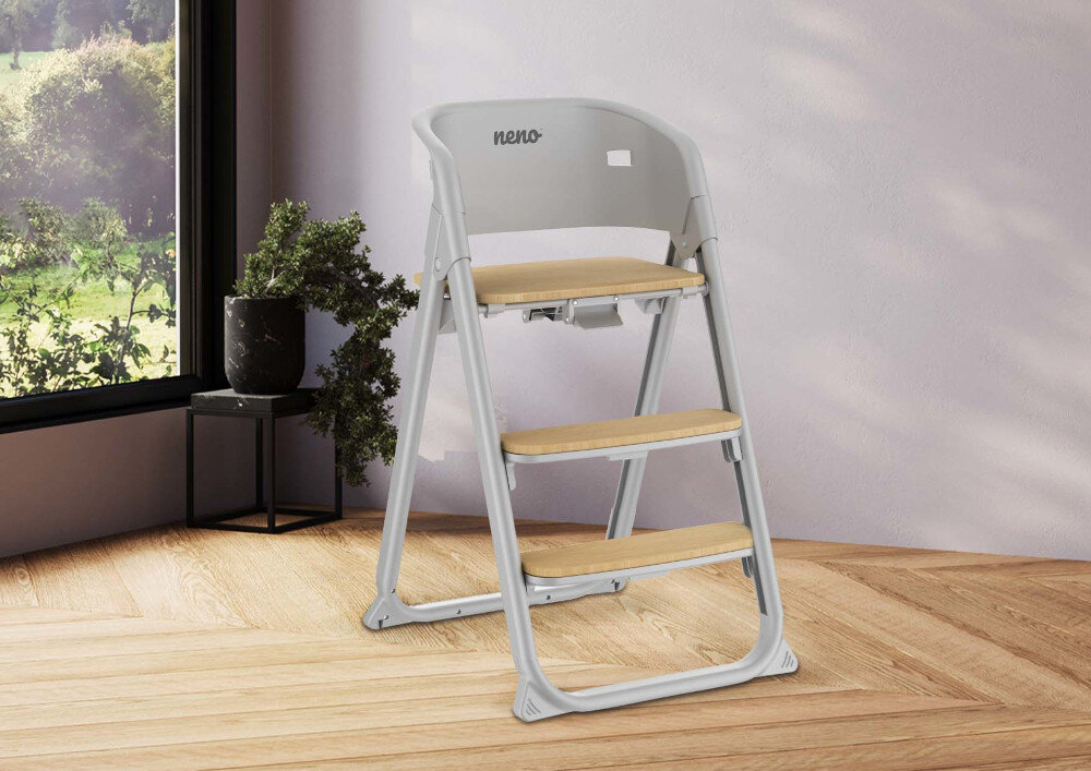 Szare krzesełko do karmienia z drewnianymi elementami stoi na drewnianej podłodze w jasnym pomieszczeniu. Na oparciu widoczne jest logo \'neno\'.
