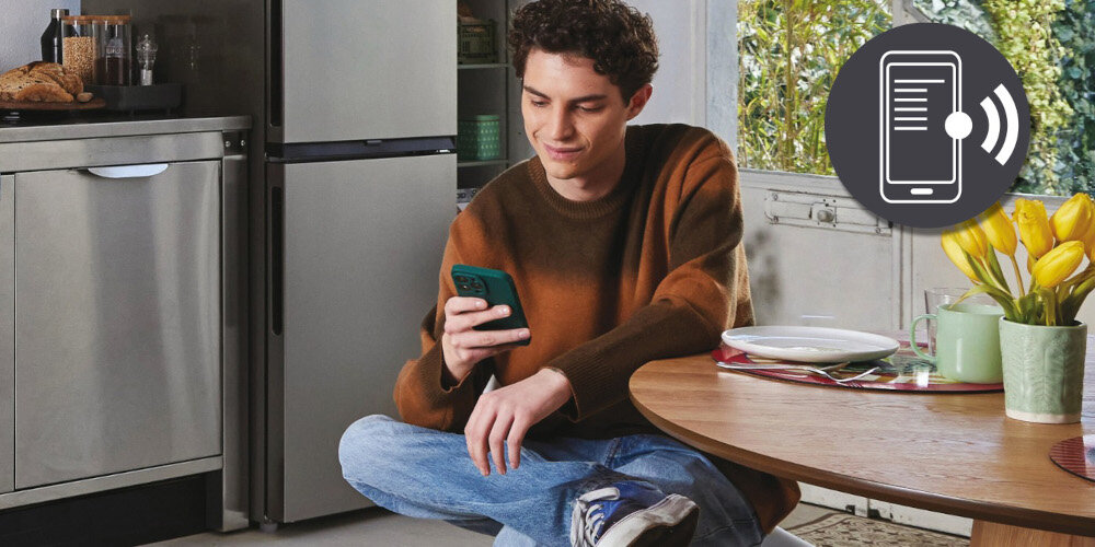 ZMYWARKA CANDY CI 4C4F1A RAPIDO zdjęcie lifestyle wizualizacja mężczyzna kuchnia żółte kwiaty wazon telefon stolik grafika aplikacja Zdalne sterowanie z hOn pełna kontrola powiadomienia przypomnienia informacje monitorowanie pracy wskazówki