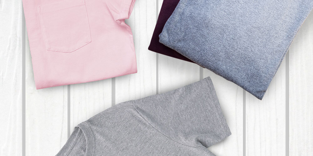 SUSZARKA BOSCH WTH85V9SPL Na zdjęciu widoczne są trzy złożone T-shirty w różnych kolorach: różowy, niebieski i szary. Leżą one na jasnej, drewnianej powierzchni. Ubrania są schludnie ułożone, co sugeruje, że zostały wyprane i złożone, gotowe do schowania do szafy tryby suszenia do prasowania do szafy ekstra suche automatyczne programy suszenia delikatne tkaniny specjalne kurtki z membraną tkaniny dwuwarstwowe bezpieczne optymalne rezultaty