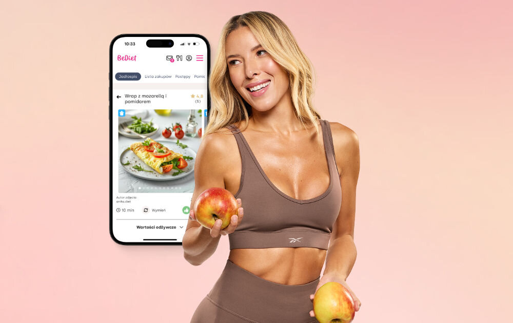 Plan dietetyczny BEDIET 12 miesięcy Uśmiechnięta Ewa Chodakowska w stroju sportowym trzymająca jabłka na tle różowego gradientu, obok smartfona z wyświetloną aplikacją dietetyczną BeDiet i przepisem na wrapa.