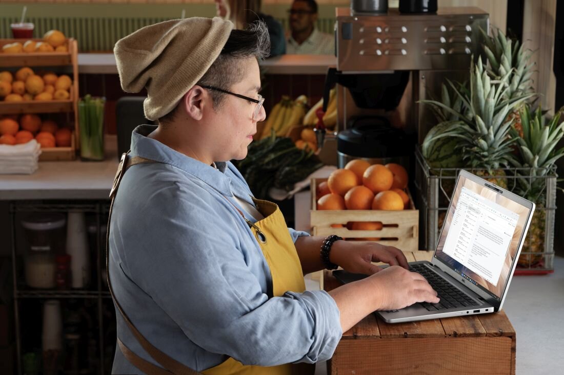 DELL Pro 13 Plus z młodym profesjonalistą pracującym w organicznym sklepie spożywczym, demonstrując ekran IPS o szerokich kątach widzenia idealny do pracy mobilnej -  AI Przekątna 13.3 z rozdzielczością 1920 x 1200 px 