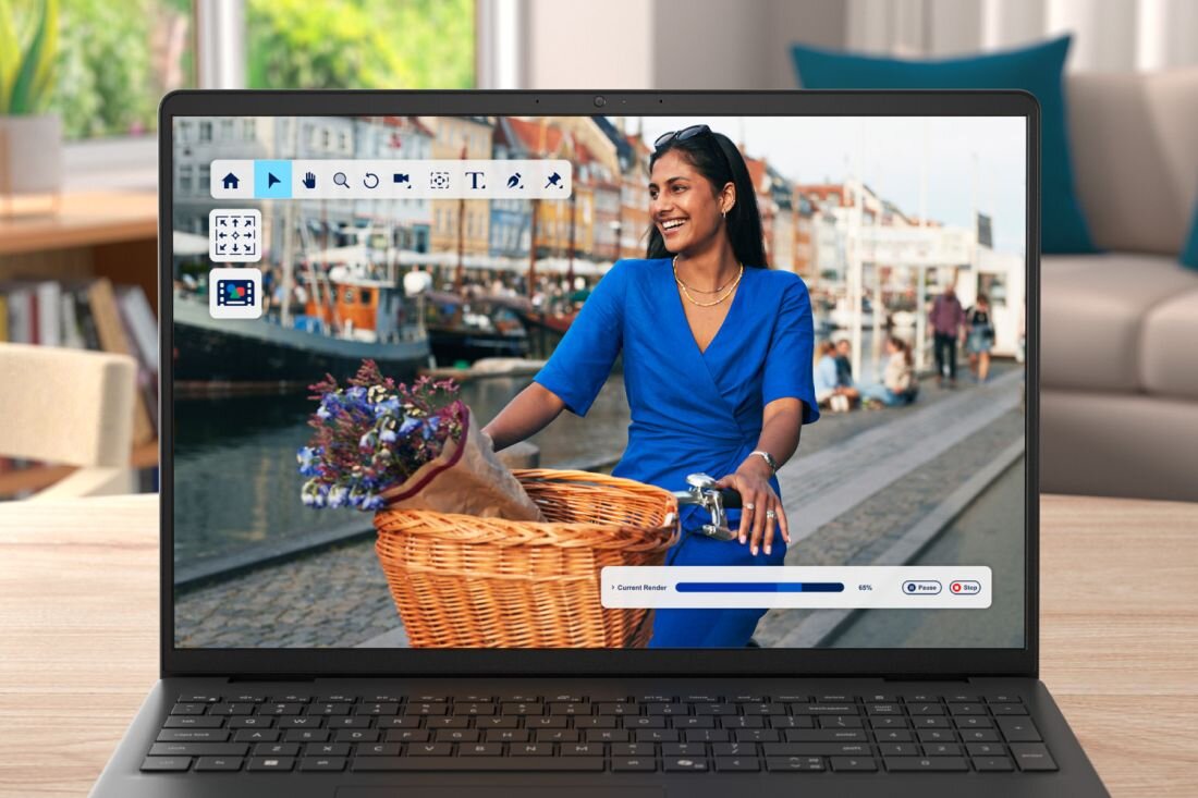 Na ekranie laptopa wyświetlony jest obraz kobiety w niebieskiej sukience, jadącej na rowerze z koszem pełnym kwiatów. W tle widać nabrzeże z łodziami i budynkami.