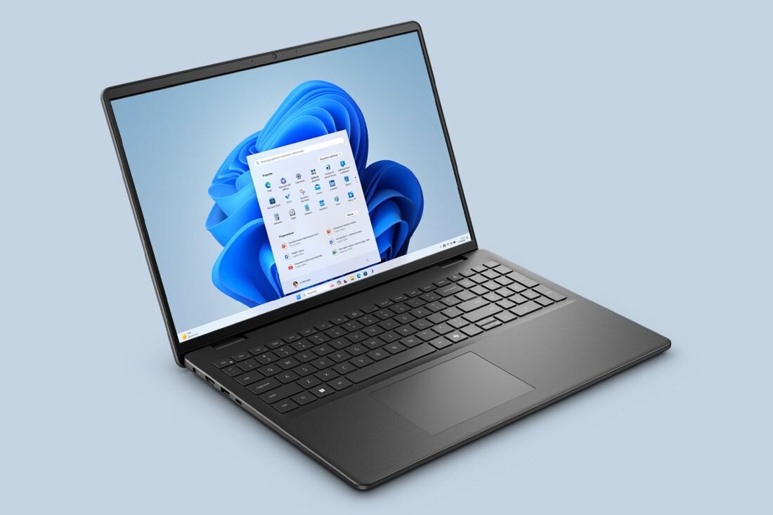Na obrazie widoczny jest otwarty laptop z wyświetlonym ekranem systemu Windows 11. Laptop ma czarną klawiaturę i duży touchpad.