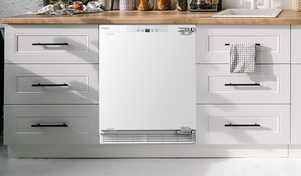 Lodówka MPM-116-CJI-17/E w jasnej zabudowie kuchennej.