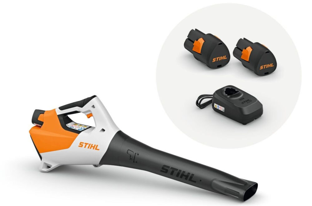 Na obrazie widoczna jest dmuchawa do liści z logo STIHL, w kolorach białym, pomarańczowym i czarnym. Obok znajdują się dwa akumulatory i ładowarka, również z logo STIHL.