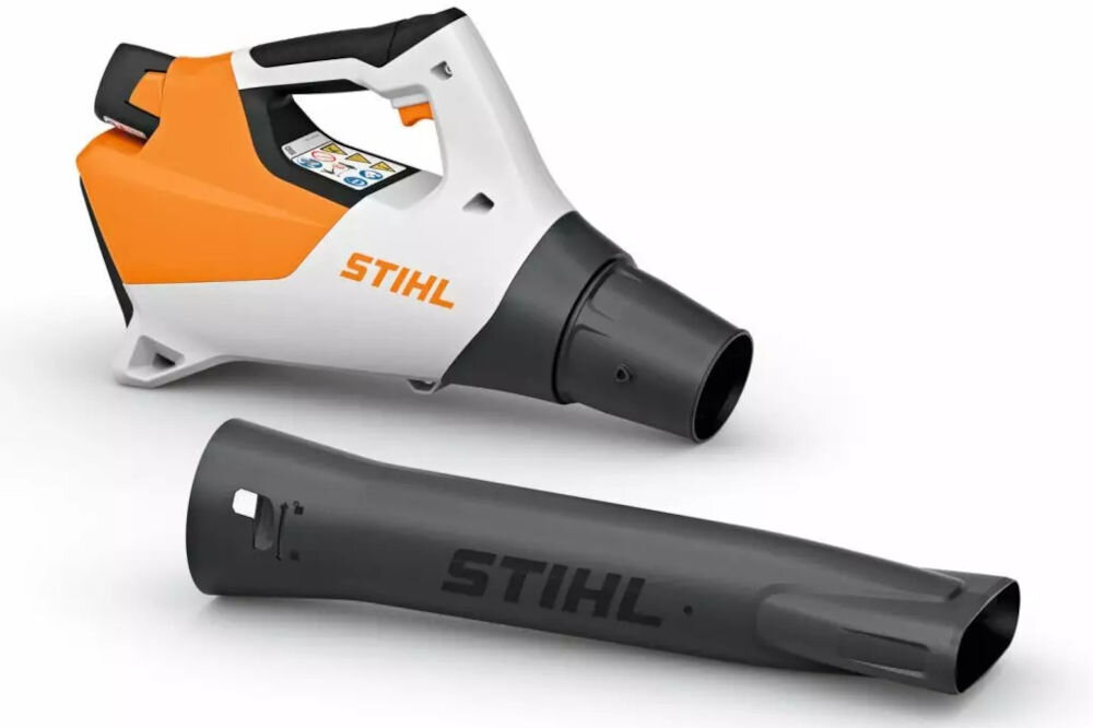 Na obrazie widoczna jest akumulatorowa dmuchawa do liści w kolorze pomarańczowo-białym z czarną dyszą, z logo \'STIHL\' na obudowie. Obok leży czarna rura z napisem \'STIHL\'.