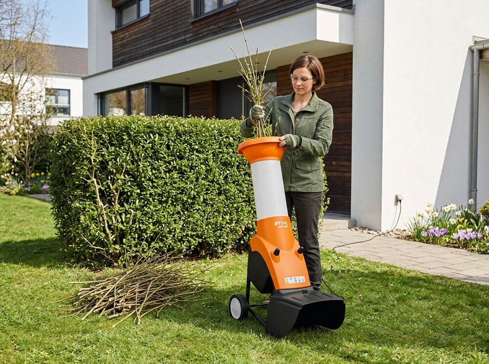 Rozdrabniacz do gałęzi STIHL GHE 250 S elektryczny 2500W średnica cięcia 35mm, rębak, elektryczny, silnik, gałęzie, Kobieta wkładająca gałęzie do rozdrabniacza w ogrodzie.