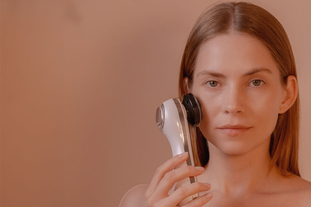 Urządzenie do mezoterapii GARETT BEAUTY Fresh Skin Pro Biały kobieta trzymająca przy twarzy urządzenie biały tył urządzenia  jasne tło Impulsy EMS działanie liftingujące, poprawia jędrność skóry i wspomaga modelowanie twarzy Prąd impulsowy o niskiej częstotliwości stymulacja mięśni wzmocnienie redukcja wiotkości masaż wibracyjny wspomaganie regeneracji komórkowej poprawa konturu twarzy pomaga pozbyć się nadmiaru tkanki tłuszczowej bardziej napięty wygląd skóry