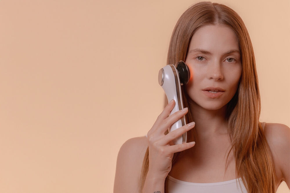 Urządzenie do mezoterapii GARETT BEAUTY Fresh Skin Pro Biały kobieta trzymająca przy twarzy urządzenie biały tył urządzenia czerwone światło jasne tło  terapię LED w trzech kolorach dostosowanie pielęgnacji Czerwone światło wspomaganie regeneracji  redukcja zmarszczek zielone pomoc w wyrównanie kolorytu zmniejszenie widoczności przebarwień niebieskie działanie antybakteryjne walka z trądzikiem i stanami zapalnymi kompleksowe dbanie o cerę praktyczne rozwiązania pielęgnacyjne 