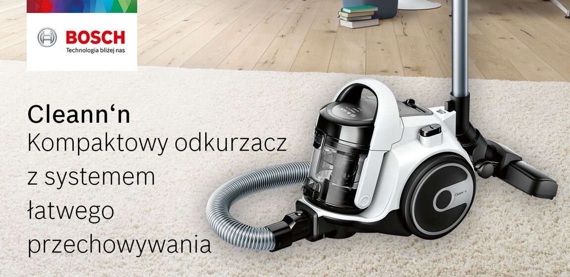 Na obrazie znajduje się odkurzacz z przezroczystym pojemnikiem na kurz, umieszczony na dywanie. Obok widoczny jest tekst: \'Cleann‘n Kompaktowy odkurzacz z systemem łatwego przechowywania\' oraz logo BOSCH z napisem \'Technologia bliżej nas\'.