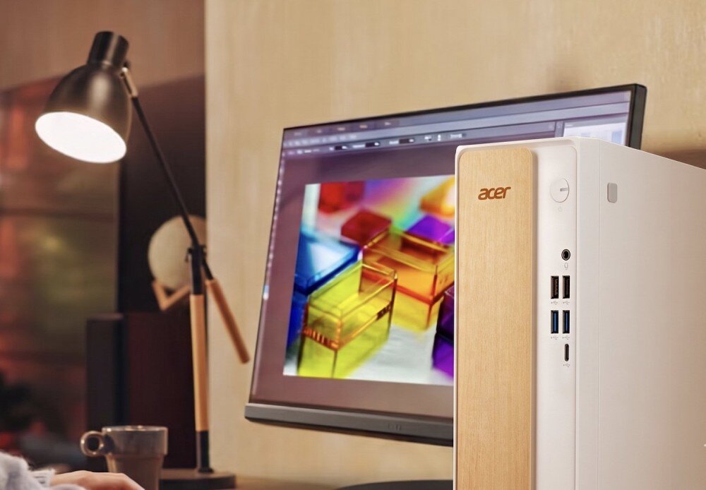 Komputer ACER Aspire XC102-RPL Komputer stacjonarny stojący na biurku obok monitora wyświetlającego grafikę, lampki oraz kubka