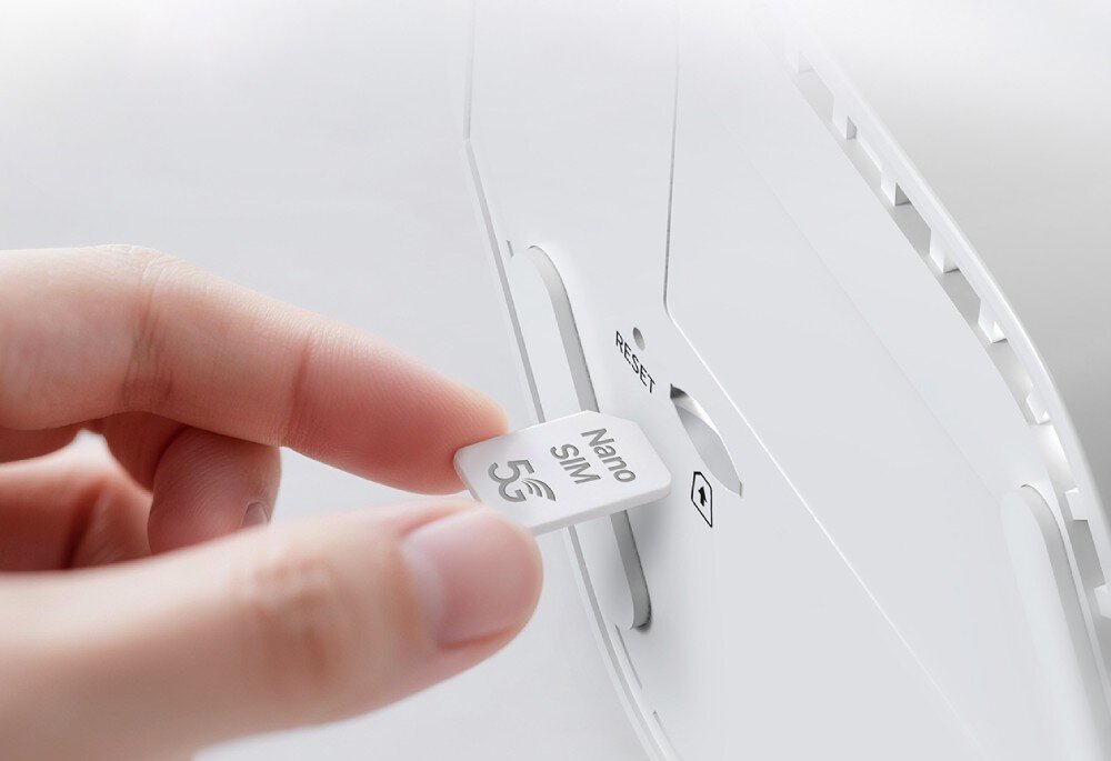 Osoba wkłada kartę Nano SIM oznaczoną \'5G\' do gniazda w urządzeniu. Obok gniazda znajduje się napis \'RESET\'.