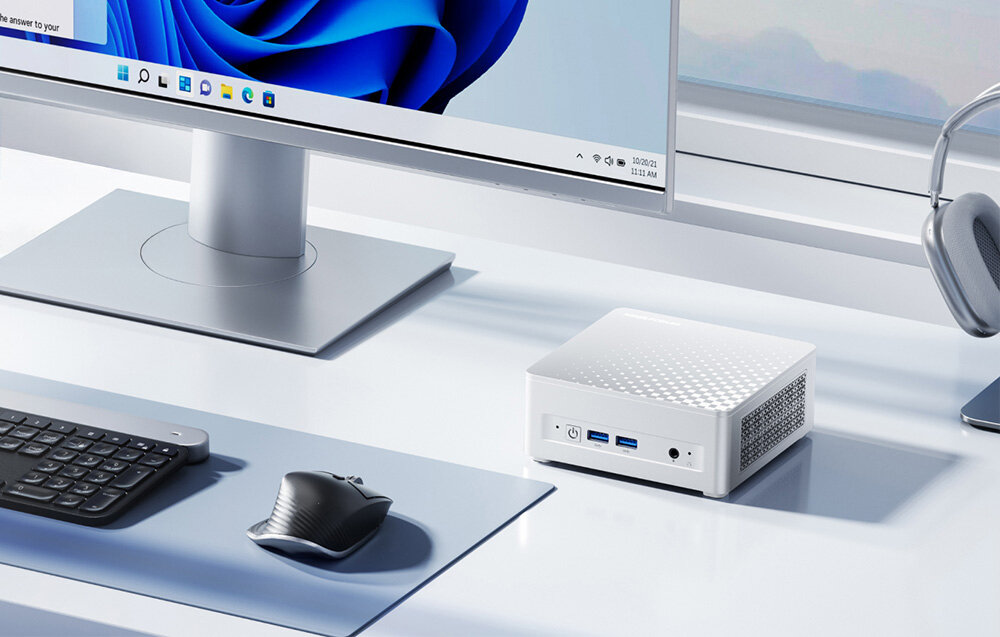 Komputer MINISFORUM M1 Plus Mini komputer na białym biurku obok monitora, myszki i klawiatury w nowoczesnym stanowisku pracy.