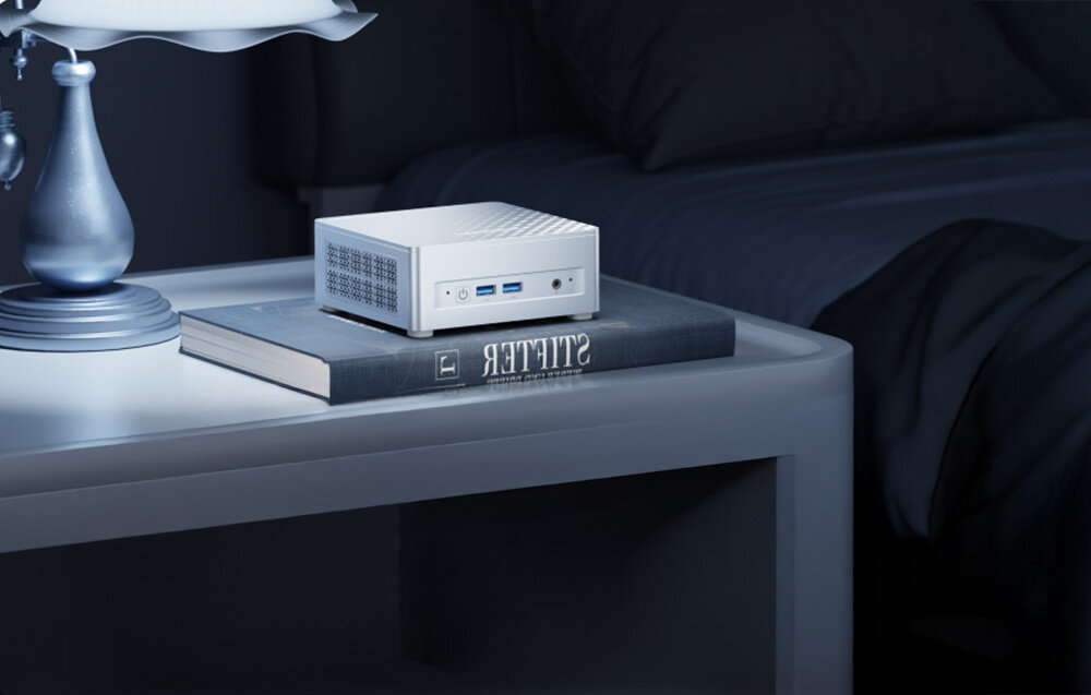 Komputer MINISFORUM M1 Plus Kompaktowy mini komputer leżący na książce na szafce nocnej, podkreślający jego niewielki rozmiar i elegancki design.