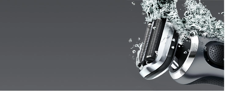 Zbliżenie na wodoodporną golarkę Braun z wodą tryskającą na ostrze.