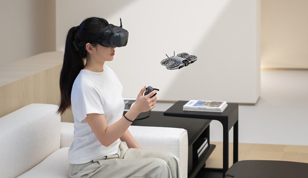 Dron DJI Neo 2 Mężczyzna w goglach i z kontrolerem jednoręcznym steruje małym dronem na tle nieba, warianty, gogle