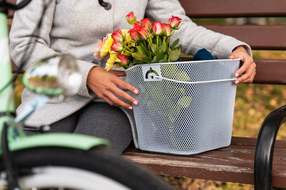 Koszyk na rower VÖGEL VKS-106 Stalowy Zdejmowany koszyk rowerowy Vogel VKS-106 trzymany przez kobietę na ławce, prezentujący funkcję przenośnego kosza na zakupy lub kwiaty