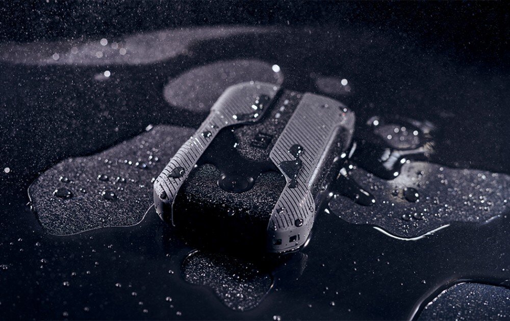 Router CAT CQ10-SAB-RON-NN 5G Zbliżenie na wilgotne urządzenie o chropowatej fakturze, na którym osiadły liczne krople wody, umieszczone na ciemnym podłożu