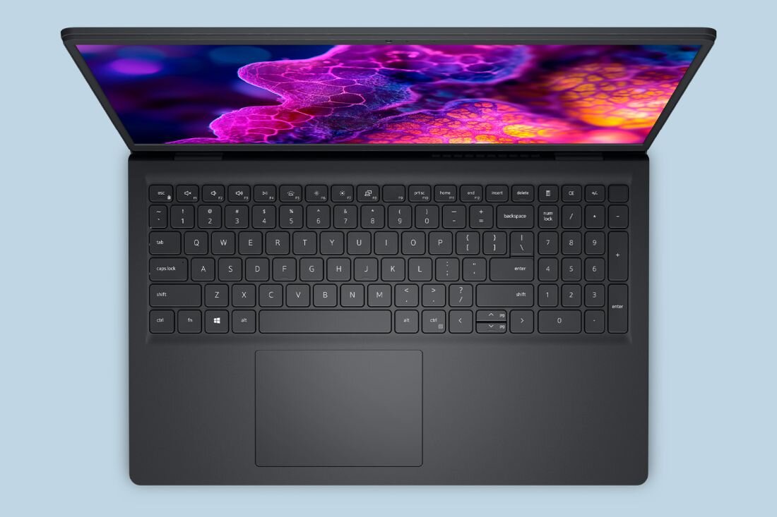 Laptop Dell 15 otwarty z góry pokazuje klawiaturę i ekran z kolorową grafiką w ujęciu studyjnym - PRZYCISK COPILOT I ASYSTENT AI 