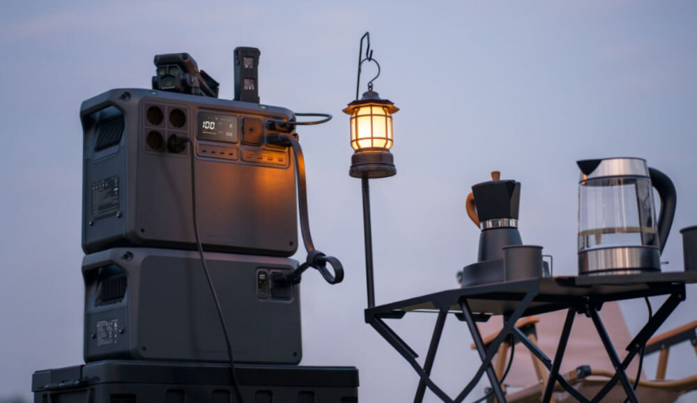 Stacja zasilania DJI Power 2000 2048 Wh Bank energii, akcesoria, ładowarki, drony, awaryjne, stacja zasilania stoi na skrzynki, w tle lampa oraz akcesoria biwakowe