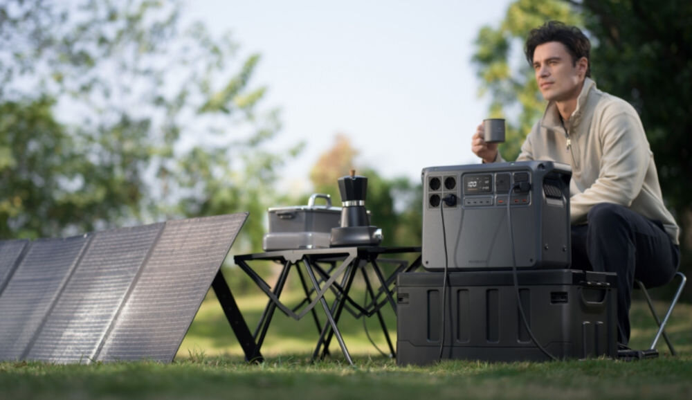 Stacja zasilania DJI Power 2000 2048 Wh Bank energii, prąd, zmienny, stały, oszczędność, mężczyzna siedzi i poje napój w tle stacja zasilania i panel fotowoltaiczny