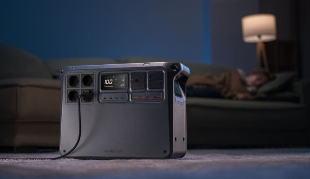 Stacja zasilania DJI Power 2000 2048 Wh Bank energii, 1 tona, odpornym, solidny, cykle, w tle lampa nocna i łóżko, na pierwszym planie stacja zasilania na podłodze