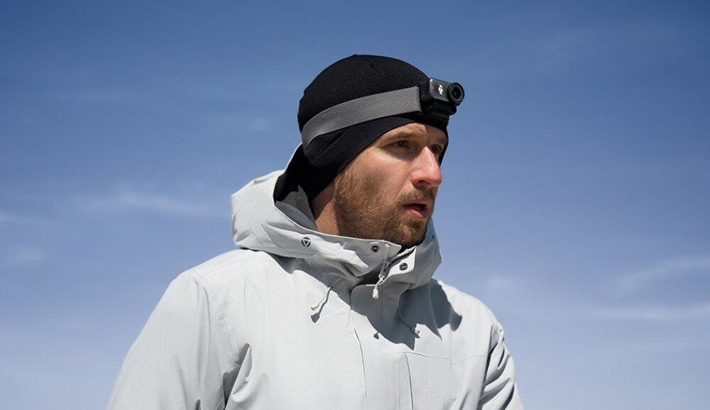 Kamera sportowa DJI Osmo Nano Mężczyzna w jasnej kurtce i czapce z zamocowaną na głowie małą kamerą, zastosowanie, cechy, jakość nagrywania