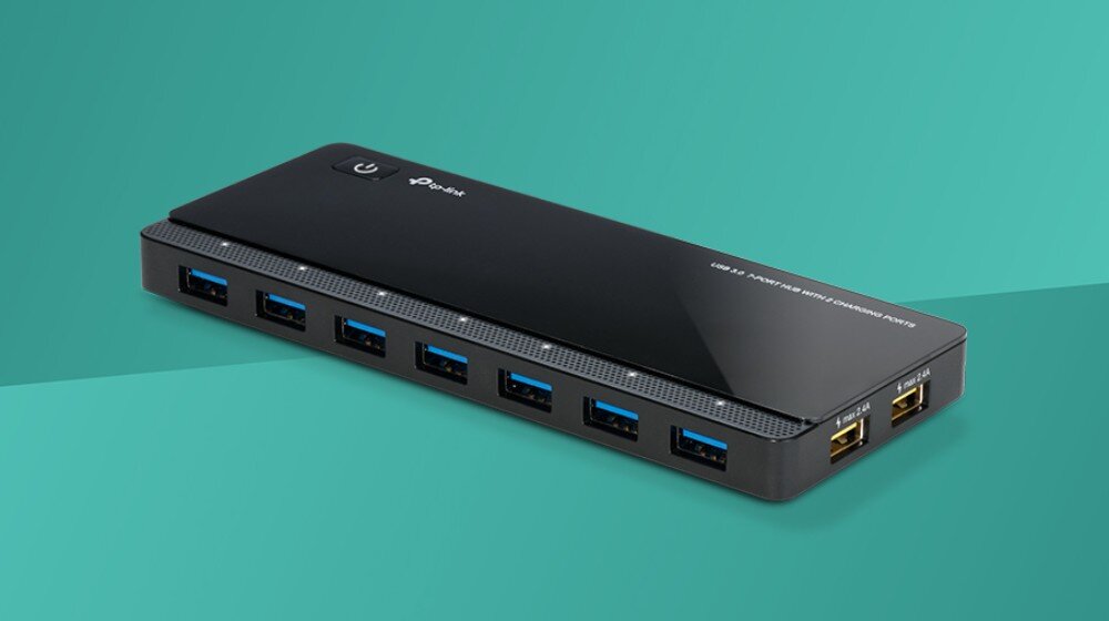 Hub TP-LINK UH720 Widok z góry pod kątem na czarny, podłużny koncentrator USB z siedmioma niebieskimi portami na dłuższym boku i dwoma żółtymi portami na krótszym boku na morskim tle